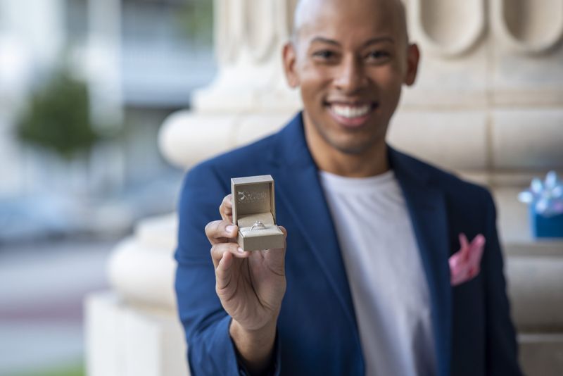 Lemar in a navy blazer holding an open ring box