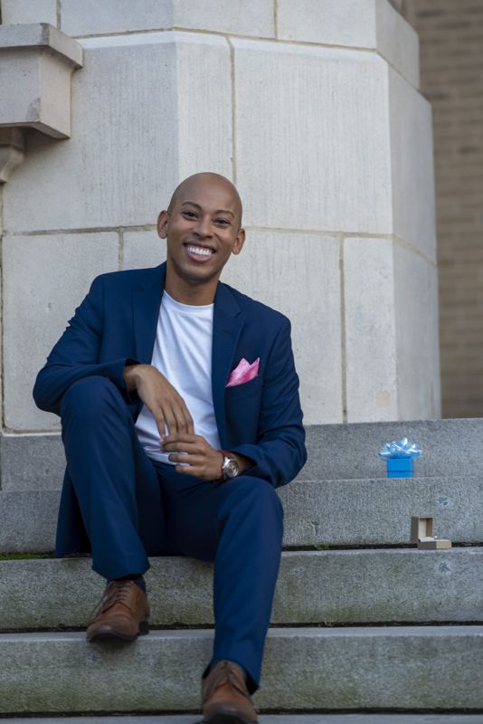 Lemar in a navy suit seated on stone steps