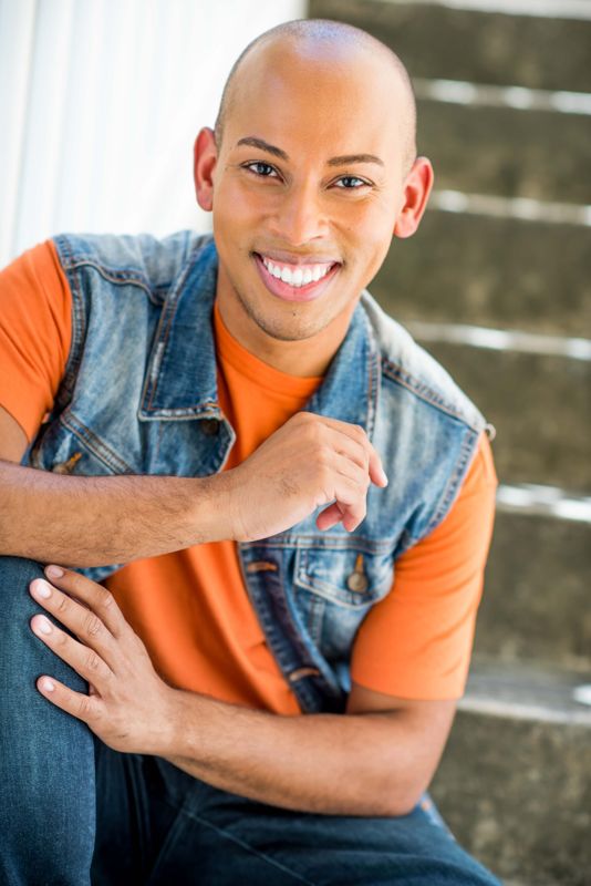 Lemar in an orange shirt and denim vest