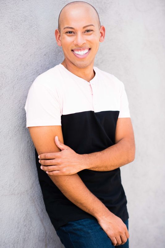 Lemar in a white and black tee, arms folded